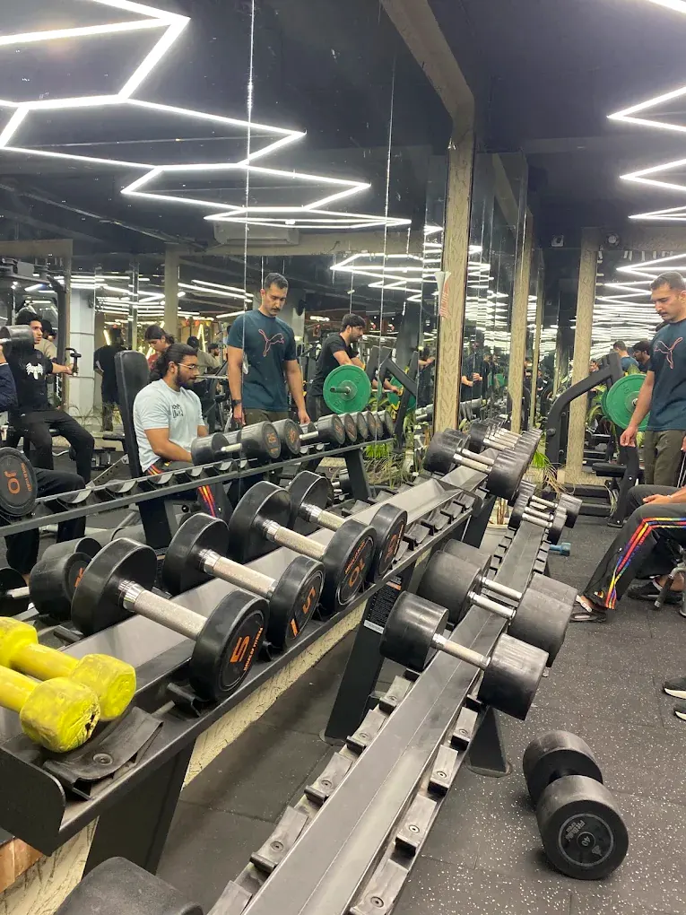 Two long dumbbell racks running down the middle of the weights floor, mirrored wall behind