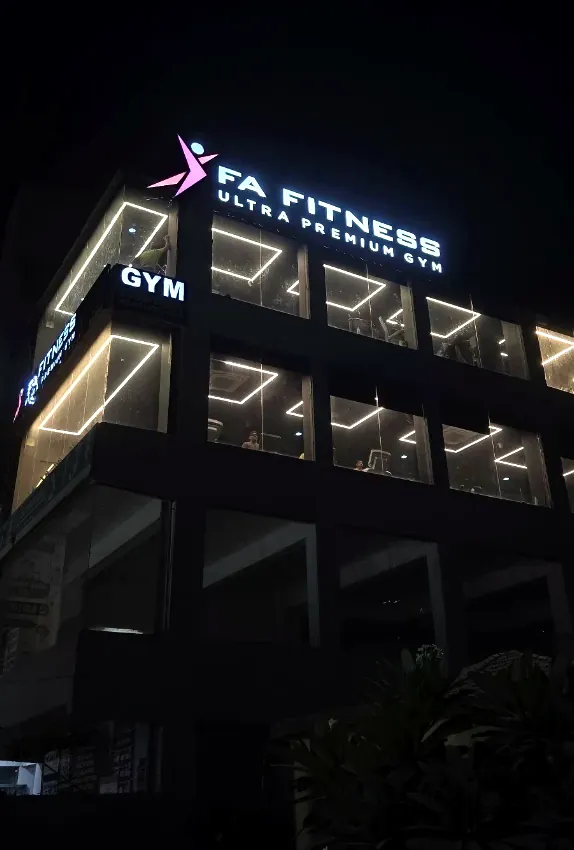 The FA Fitness building at night, its windows outlined in LED strips and the lit sign on the roof