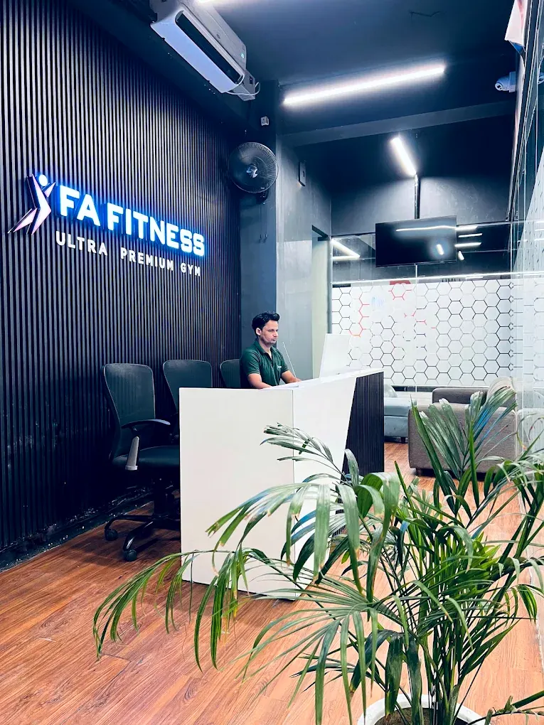The reception desk at FA Fitness, with the backlit sign on the black fluted wall behind it