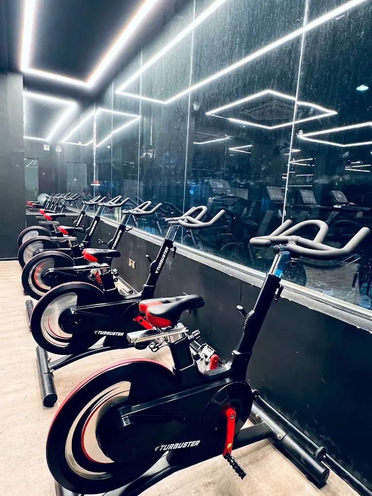 A row of spin bikes facing a mirrored wall in the indoor cycling studio